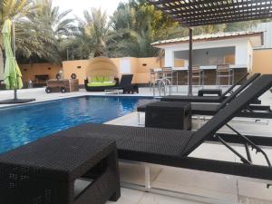 a swimming pool with chairs and a table next to a resort at The Inn Nizwa in Nizwa