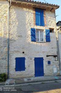 un edificio con persianas azules y una ventana en Gîte Le Lau-Kal, en Septfonds