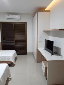 Habitación con 2 camas y escritorio con TV. en Rosa Vilma Hotel, en Chapadão do Sul