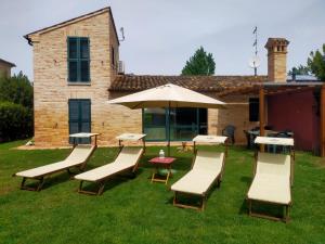 - un groupe de chaises et une table avec un parasol dans l'établissement Villetta del Conero, à Porto Recanati