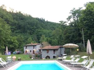 una casa y una piscina con sillas y sombrilla en Relax totale nel Bosco Lucca, en Ghivizzano