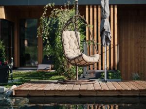 uma cadeira sentada num pátio ao lado de uma piscina em Hotel MorgenZeit -Natürlich.Bed&Brunch em Maria Alm am Steinernen Meer