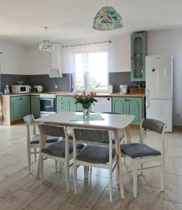 a kitchen with green cabinets and a white table and chairs at Rodzinny Apartament na Kaszubach in Brusy
