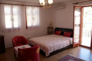 a bedroom with a bed and a chair and windows at Apartments Morski Vuk in Tivat