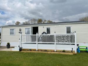 a white mobile home with a porch and a fence at Hutchinson's Willerby Kelston with Hot tub in Cottam