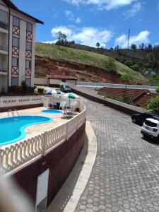 a building with a swimming pool next to a parking lot at Apartamento Diamante in Águas de Lindoia