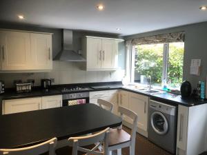 a kitchen with white cabinets and a black counter top at Rose Cottage in Inverness