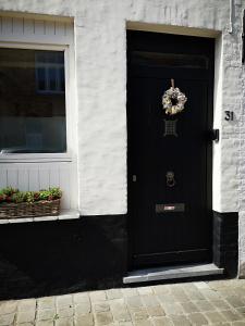 a black door with a wreath on it next to a window at B&B Riverside - Centre of Bruges in calm area in Bruges