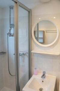 W łazience znajduje się prysznic, umywalka i lustro. w obiekcie Haus am Meer w mieście Scharbeutz