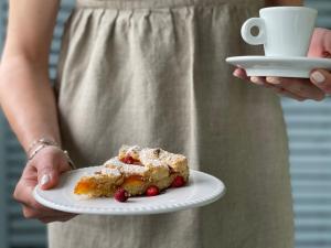 a person holding a plate with a piece of cake and a cup of coffee at Le Village Sarzana in Sarzana