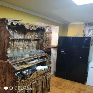 uma cozinha com um armário de madeira com pratos e um frigorífico em Like Home Hostel em Tiraspol