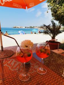 two wine glasses sitting on a table next to the beach at Pension Alba in Podstrana