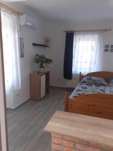 - une chambre avec un lit en bois et 2 fenêtres dans l'établissement Oázis Apartman, à Sárospatak