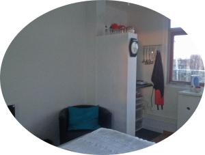 ein Zimmer mit einem Stuhl und einer Uhr an der Wand in der Unterkunft B&B 2 Hoog Lelystad in Lelystad