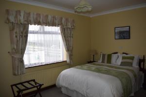 um quarto com uma cama grande e uma janela em Cois Farraige em Lahinch