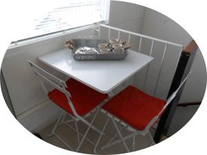 a small white table with two red chairs and a window at B&B 2 Hoog Lelystad in Lelystad