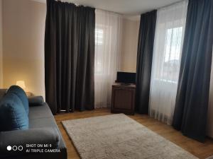 a living room with curtains and a couch and a television at Apartments Domovik on Beregovskaya 3 in Mukacheve