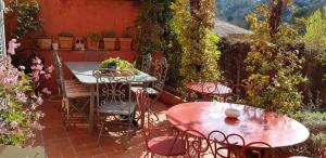 un patio con 2 mesas, sillas y flores en Le Belvédère - Chambres d'hôtes de charme et Restaurant, en Flassans-sur-Issole