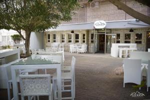 um restaurante com mesas e cadeiras brancas em frente a um edifício em Tabar Hotel na Nazaré