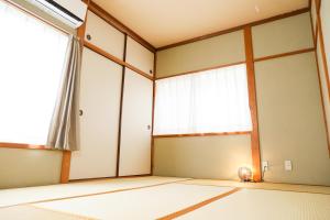 um quarto vazio com uma janela e um gato sentado no chão em HAT Kujo, near from Kintetsu Kujo station 近鉄九条駅前の民泊 em Kōriyama