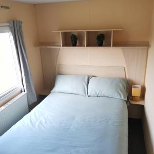 um quarto com uma cama com dois vasos de plantas nas prateleiras em No99 Static Caravan Widemouth Fields 3 mins from beach em Poundstock