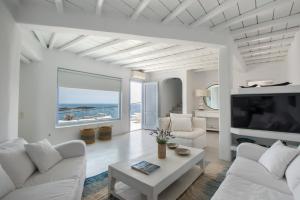 a living room with white furniture and a large window at Villa Isabella - Psarou in Psarou