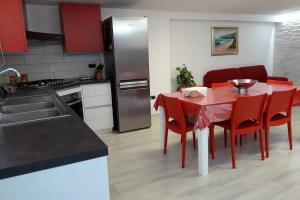 a kitchen with a table with red chairs and a refrigerator at Incantos Charme B&B & Apartment in Tortolì