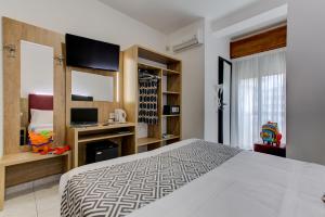 una camera con un grande letto e una TV di Hotel Grazia Riccione a Riccione