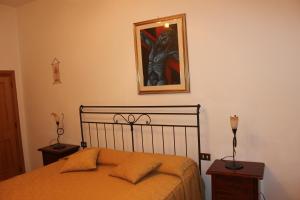 サン・ジミニャーノにあるIl Vecchio Cipressoのベッドルーム1室(ベッド1台付)が備わります。壁に絵が飾られています。
