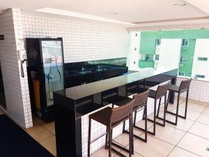 a kitchen with a bar with chairs and a sink at Apartamento de 2 quartos com pé na areia em Manaíra in João Pessoa