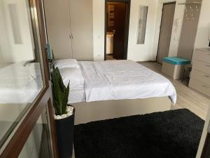 sypialnia z białym łóżkiem i doniczką w obiekcie Le Nid - your central destination w Jassach