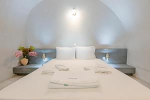 a white bed with white pillows and towels on it at NONI STUDIOS in Fira