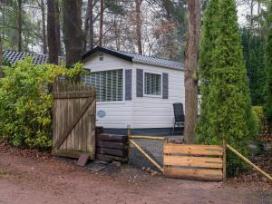 une petite cabine blanche avec un portail et une clôture dans l'établissement Beautiful Holiday Chalet in Emst with a private garden, à Emst