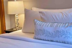 a bed with white pillows and a table with a lamp at Windtower Lodge FullKitchen-Kingbed Suite-MntView-UGParking-Walk2DT in Canmore