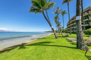 Wonderful Maui Vista-Kihei Kai Nani Beach Condos في كيهي: اطلالة على شاطئ فيه نخل ومبنى