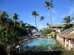 a large swimming pool with chairs and palm trees at Wonderful Maui Vista-Kihei Kai Nani Beach Condos in Kihei