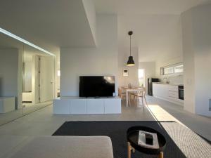 a white living room with a tv and a table at Arvore Beach House in Árvore