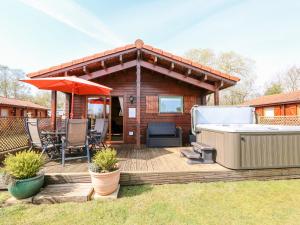 een houten terras met een hot tub en een prieel bij Bittern Lodge in Tattershall