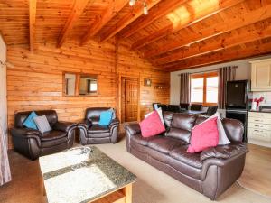 a living room with leather couches and a television at Bittern Lodge in Tattershall