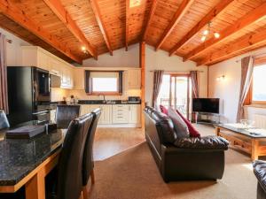 a living room with leather chairs and a kitchen at Bittern Lodge in Tattershall