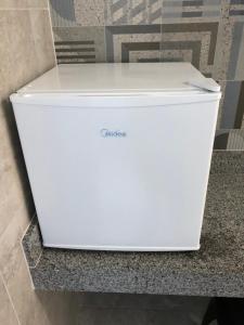 a white refrigerator sitting on a counter in a bathroom at Apt no centro,a 800mts do pátio do forró in Caruaru +7 photos