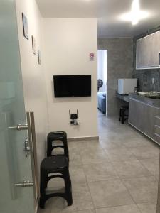 a living room with two chairs and a tv on a wall at Apt no centro,a 800mts do pátio do forró in Caruaru
