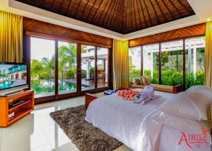 a bedroom with a bed and a tv and windows at Airis Luxury Villas and Spa in Uluwatu