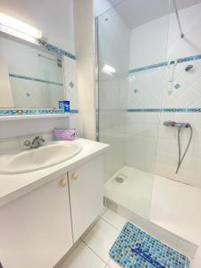 ein weißes Bad mit einem Waschbecken und einer Dusche in der Unterkunft Appartement bord de mer in Sainte-Anne