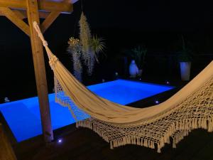 eine Hängematte auf einer Terrasse in der Nacht mit einem Pool in der Unterkunft Villa Pelican Lodge in Deshaies