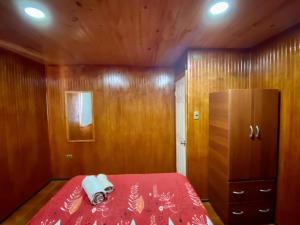a bedroom with a red bed and a wooden wall at Depto N°4 Temuco Centro in Temuco