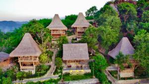 an aerial view of a group of houses with thatched roofs at Elang Hillside Bamboo Villas in Labuan Bajo