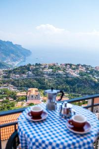 a table with two cups and a tea pot on a balcony at Appartamento Andrea in Ravello