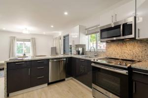 uma cozinha com armários pretos e electrodomésticos de aço inoxidável em Casa Madeira 2@ the heart of Miami Design District em Miami