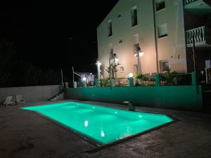 ein Schwimmbad vor einem Gebäude in der Nacht in der Unterkunft Apartmani Ivan V RELAX in Vodice